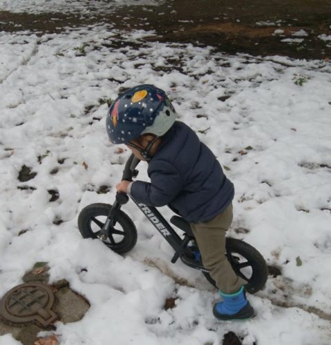 雪の中ストライダーに乗る2歳児